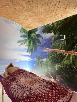 a woman laying on a bed with a palm tree mural at Hotel Emonec in Ljubljana