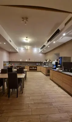 a cafeteria with tables and chairs and a kitchen at Hotel Emonec in Ljubljana
