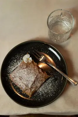 a black plate with a piece of bread and a fork at Török rooms, bistro & wellness in Lesce