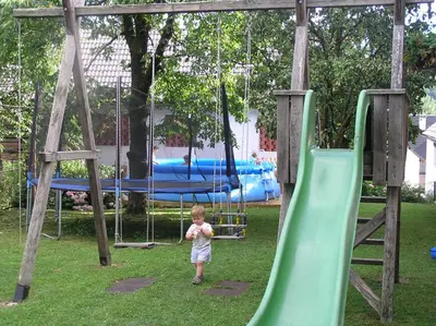 a young child standing on a slide at a playground at Boutique Hotel Loka in Škofja Loka