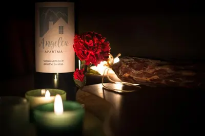 a bottle of wine and candles and a flower on a table at Apartma Angelca in Kranjska Gora