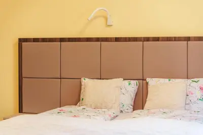 a bed with a large padded headboard and pillows at Dvorec Trebnik - SOBE in Slovenske Konjice