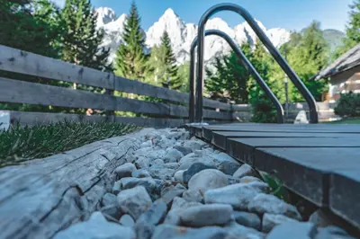 a walkway with rocks and a fence and mountains at Hiša Katja-Privat wellness in Kranjska Gora