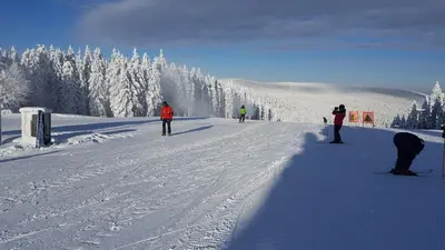 a group of people skiing down a snow covered slope at Rogla app Jerebika 11 in Zreče