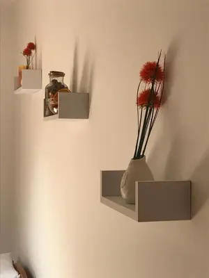 two shelves on a wall with a vase with flowers in it at Charming Apartments Ana in Maribor