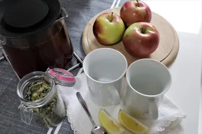 a table with three cups and apples on a cutting board at Charming Apartments Ana in Maribor