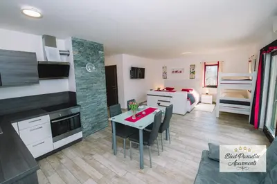 a kitchen and living room with a table and a room with a bed at Bled Paradise Apartments in Bled