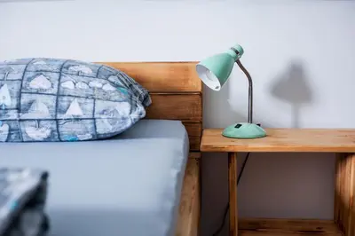 a lamp sitting on a desk next to a bed at Apartmaji Pri Kozmavo - Little House in Bohinj