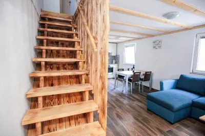 a wooden staircase in a living room with a blue couch at Apartmaji Pri Kozmavo - Little House in Bohinj