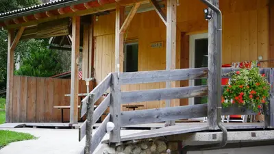 a wooden cabin with a porch with a fence at Apartmaji Pri Kozmavo - Little House in Bohinj