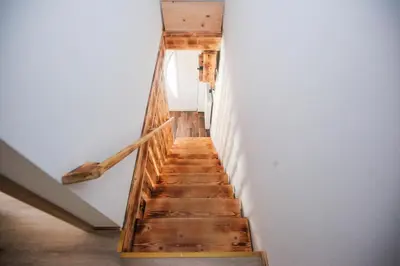 a wooden staircase in a room with a window at Apartmaji Pri Kozmavo - Little House in Bohinj