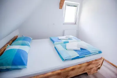 a bed with blue and white pillows and a window at Apartmaji Pri Kozmavo - Little House in Bohinj