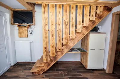 a wooden staircase in a room with a tv at Apartmaji Pri Kozmavo - Little House in Bohinj