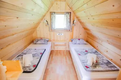 two beds in a small room with wooden walls at Apartmaji Pri Kozmavo - Little House in Bohinj