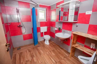 a red and white bathroom with a toilet and a sink at Apartmaji Pri Kozmavo - Little House in Bohinj