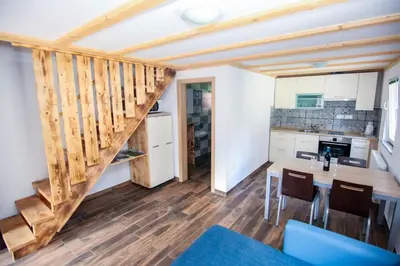 a kitchen and dining room with a staircase in a tiny house at Apartmaji Pri Kozmavo - Little House in Bohinj