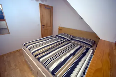a bed with striped sheets in a small room at Apartmaji Lajf in Kranjska Gora