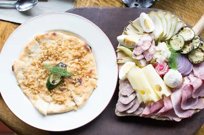 a plate of food with a pizza and a plate of vegetables at Taverna & Wine Jeruzalem in Ivanjkovci