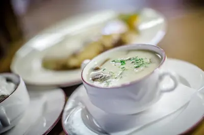 a cup of soup on a table with a plate of food at Taverna & Wine Jeruzalem in Ivanjkovci