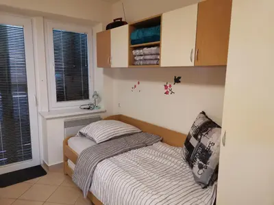 a small bedroom with a bed and two windows at Apartma Gaber 80 in Zreče