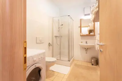 a bathroom with a shower toilet and a washing machine at Apartma Luna in Kranjska Gora
