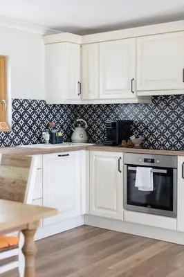 a kitchen with white cabinets and a black and white wallpaper at Holiday Home Virida, app Leopold III in Ivančna Gorica