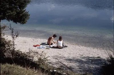 a man and woman sitting on the beach near the water at PRIVILLAGE Stare - B&B in Bohinj