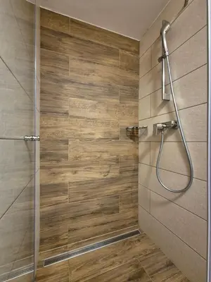 a shower in a bathroom with a wooden wall at PRIVILLAGE Stare - B&B in Bohinj