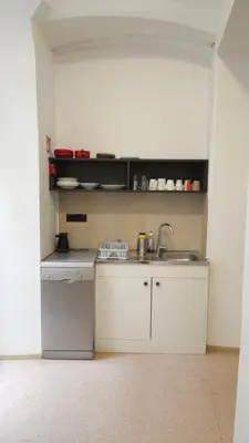 a small white kitchen with a sink and a counter at AdHoc Hostel in Ljubljana