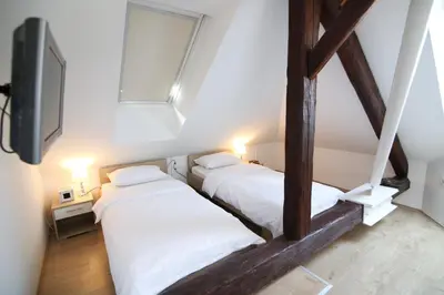 two beds in a room with a tv and a window at Hotel Katrca in Ljubljana