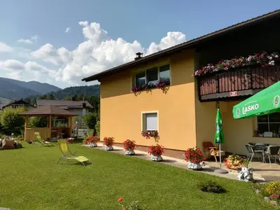 a yellow building with a green yard with chairs and a building at TURISTIČNA KMETIJA LIPNIK in Lovrenc na Pohorju
