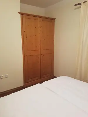a bedroom with a wooden cabinet next to a bed at Apartma Lenka Kranjska Gora in Kranjska Gora