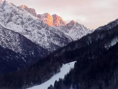 a mountain range with a lake in the foreground at Julija Podkoren in Kranjska Gora