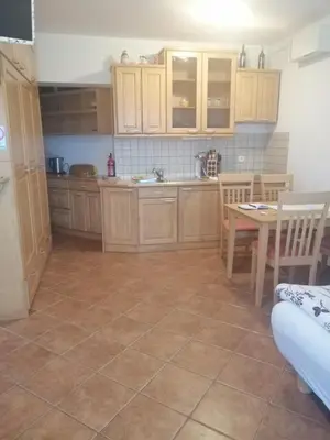 a kitchen with wooden cabinets and a table and chairs at Julija Podkoren in Kranjska Gora