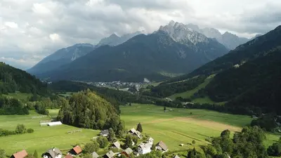 a green field with houses in a valley with mountains at Julija Podkoren in Kranjska Gora