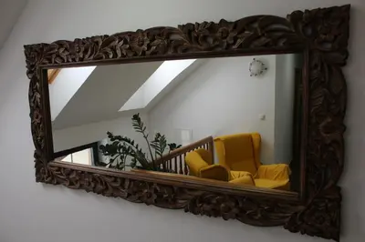a mirror hanging on a wall with a yellow chair at Vdovič Guest House in Svečina