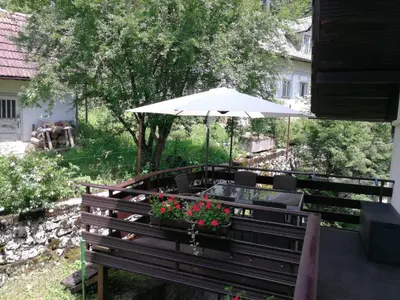 a bench with an umbrella and flowers on it at Apartment KLEMEN in Bohinjska Bela