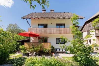 a house with a red umbrella in front of it at Apartma Peček Kranjska Gora in Kranjska Gora