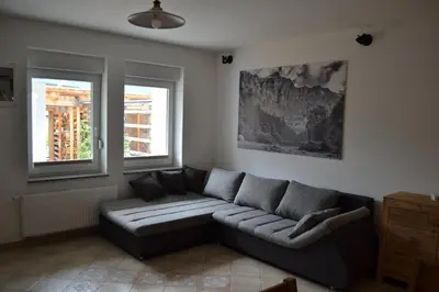 a living room with a couch and two windows at ALPIN apartma in Bovec