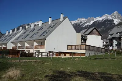a large white building with mountains in the background at ALPIN apartma in Bovec