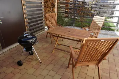 a patio with a grill and a wooden table and chairs at ALPIN apartma in Bovec