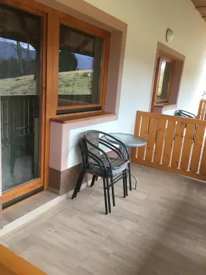 a table and chairs on a porch with windows at Ranch Marina in Koče