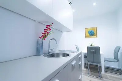 a white kitchen with a sink and two chairs at Apartma City & Free Parking in Ljubljana