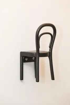 a black chair hanging on a white wall at Big yard in Ljubljana