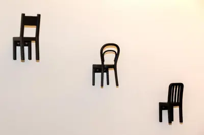 a group of three chairs sitting on a white wall at Big yard in Ljubljana