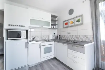 a white kitchen with white appliances and a window at Mateja House - Apartments in Žirovnica in Rodine