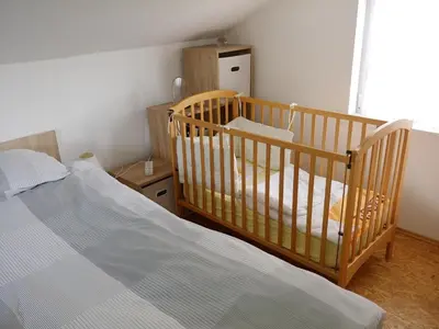 a bedroom with a crib and a bed at Apartma PEPI in Rogaška Slatina