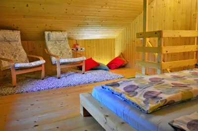 a bedroom with two beds and chairs in a log cabin at Sleeping with the bees Kozjak in Kobarid