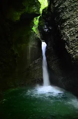 a waterfall in a cave with green water at Sleeping with the bees Kozjak in Kobarid
