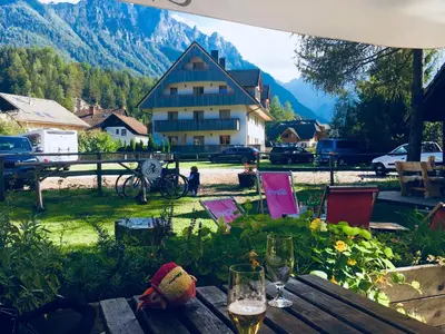 a table with wine glasses and a house in the background at Vall’s apartment- by ski slopes in Kranjska Gora